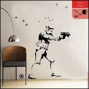 May include: Black and white silhouette wall decal of a Star Wars Stormtrooper holding a blaster, with a background of small stars. The decal is on a white wall.