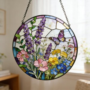 May include: A round stained glass window featuring a garden scene with lavender, pink, yellow, and blue flowers, and a purple butterfly. The window is framed in black and hangs from a chain.