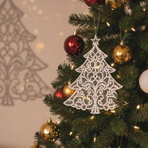 May include: A white, intricately designed Christmas tree ornament with a star on top hangs on a decorated evergreen tree. The ornament is approximately 3 to 6 inches in size. The text "ORNAMENT EMBROIDERY" and "3" TO 6" SIZES" are displayed.