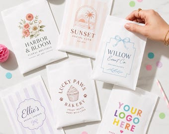 Könnte beinhalten: Fünf weiße Papiertüten mit verschiedenen individuellen Aufdrucken, darunter Blumenarrangements, eine Sonnenuntergangsszene, eine blaue Schleife, ein Cupcake und bunter Text. Die Tüten tragen die Aufschriften Harbor & Bloom, Sunset Social Club, Willow Event Co., Ellie's und Lucky Paws Bakery.