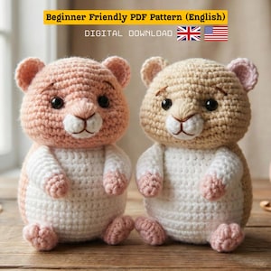 May include: Two crocheted hamster toys, one pink and white, the other tan and white. They have black eyes and pink accents. The image includes text: "Beginner Friendly PDF Pattern (English)" and "DIGITAL DOWNLOAD". The UK and US flags are also visible.