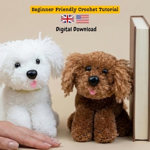 May include: Two crochet toy dogs, one white and one brown, sit beside a book. The white dog has a gold collar. The image includes text that reads "Beginner Friendly Crochet Tutorial" and "Digital Download" with the flags of the UK and the USA.