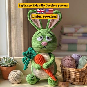 May include: A handmade green crochet bunny holding an orange carrot, with a cream-colored belly and pink inner ears. The bunny sits on a wooden shelf with a small succulent plant and yarn. Text on the image reads "Beginner Friendly Crochet pattern" and "Digital Download".