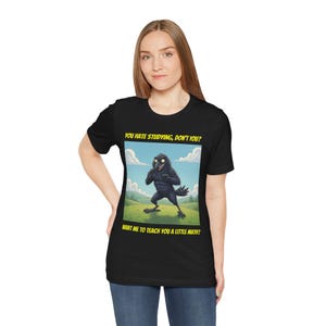 以下が含まれることがあります： 黒いTシャツ。漫画のカラスのような生き物が描かれており、テキストは「YOU HATE STUDYING, DON'T YOU? WANT ME TO TEACH YOU A LITTLE MATH?」です。イラストは、青い空の下、緑の野原にいる生き物を描いています。
