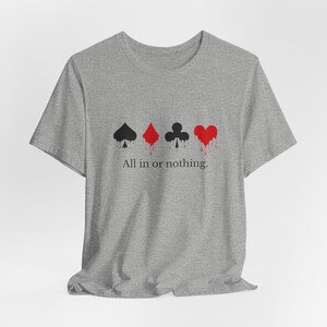 K&ouml;nnte beinhalten: Graues T-Shirt mit Spielkartensymbolen: Pik, Karo, Kreuz und Herz, mit roten Tropfeffekten. Der Text "All in or nothing" steht darunter. Das T-Shirt ist aus weichem Material.
