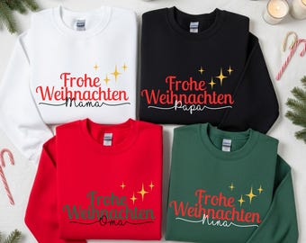 Pode incluir: Quatro camisolas de gola redonda em branco, preto, vermelho e verde. Cada camisola tem a frase alemã "Frohe Weihnachten" com um nome diferente por baixo em fonte cursiva. Tema natalino com elementos decorativos.