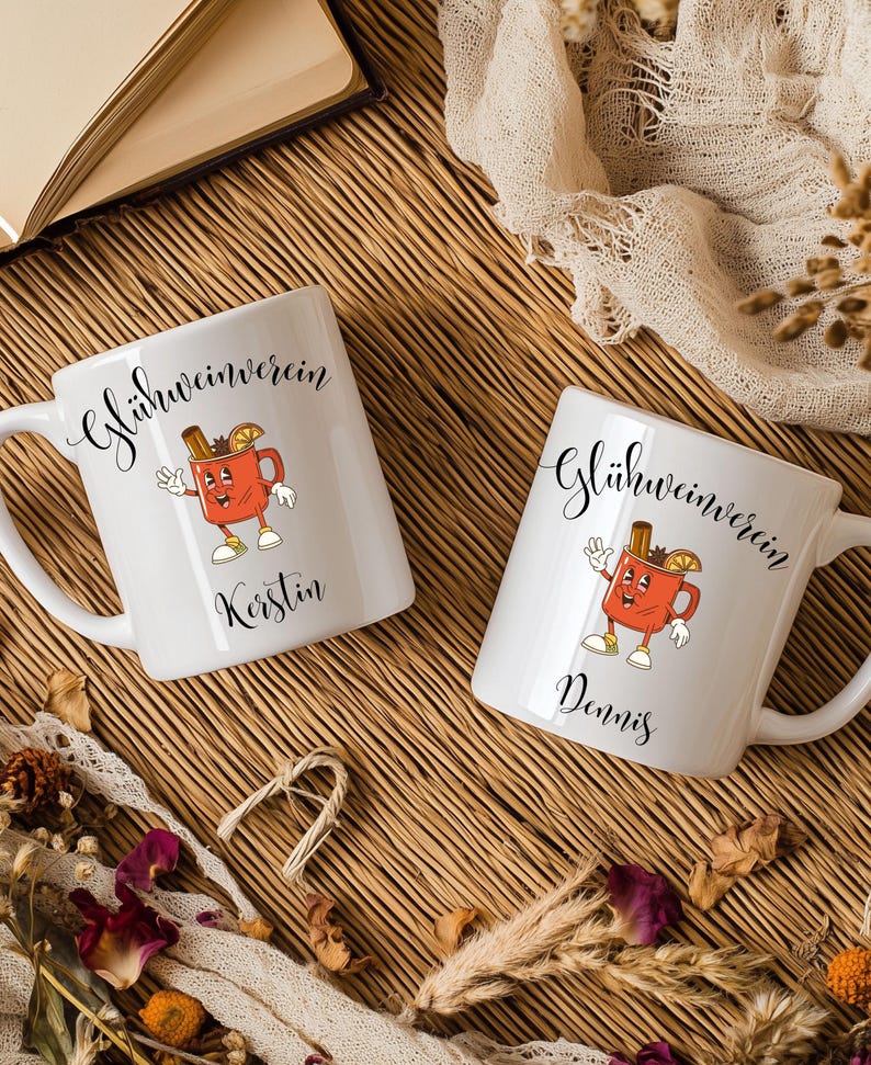 Pu&ograve; includere: Due tazze in ceramica bianca con la scritta "Gl&uuml;hweinverein" in corsivo. Ogni tazza presenta un'immagine a cartoni animati di una tazza rossa con un bastoncino di cannella e una fetta d'arancia. Una tazza &egrave; personalizzata con il nome "Kerstin", l'altra con "Dennis".