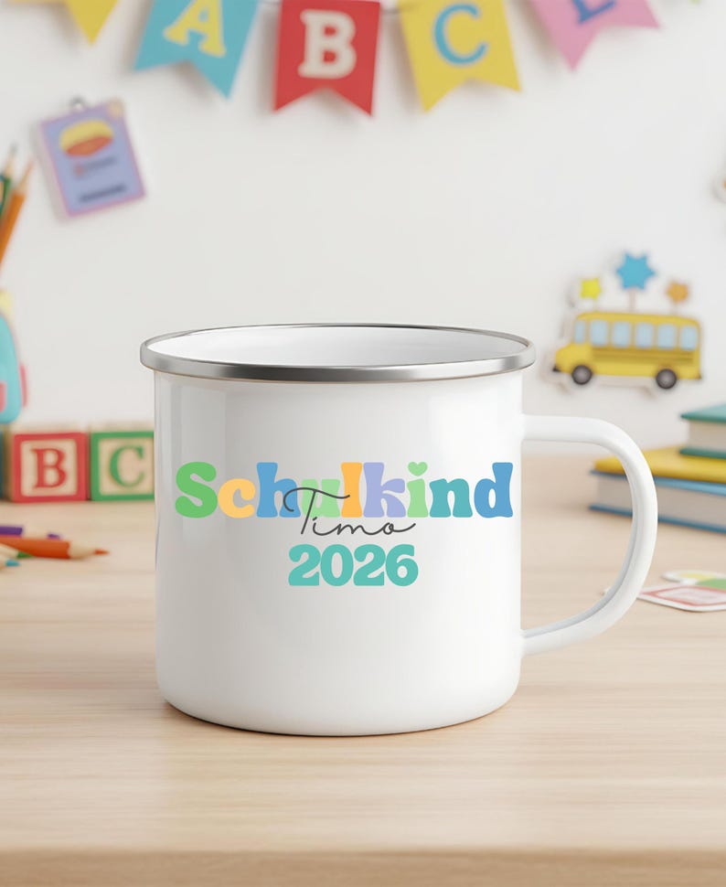 May include: A white enamel mug with a silver rim featuring the colourful text Schulkind, the name Timo in black script, and the year 2026 in teal. The mug has a side handle and a smooth finish, displaying a vibrant design on the front surface.