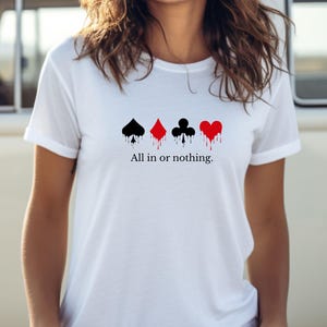 K&ouml;nnte beinhalten: Wei&szlig;es T-Shirt mit vier Spielkartenfarben: Pik, Karo, Kreuz und Herz, jeweils mit einem Tropfeffekt. Der Text "All in or nothing" ist darunter gedruckt.