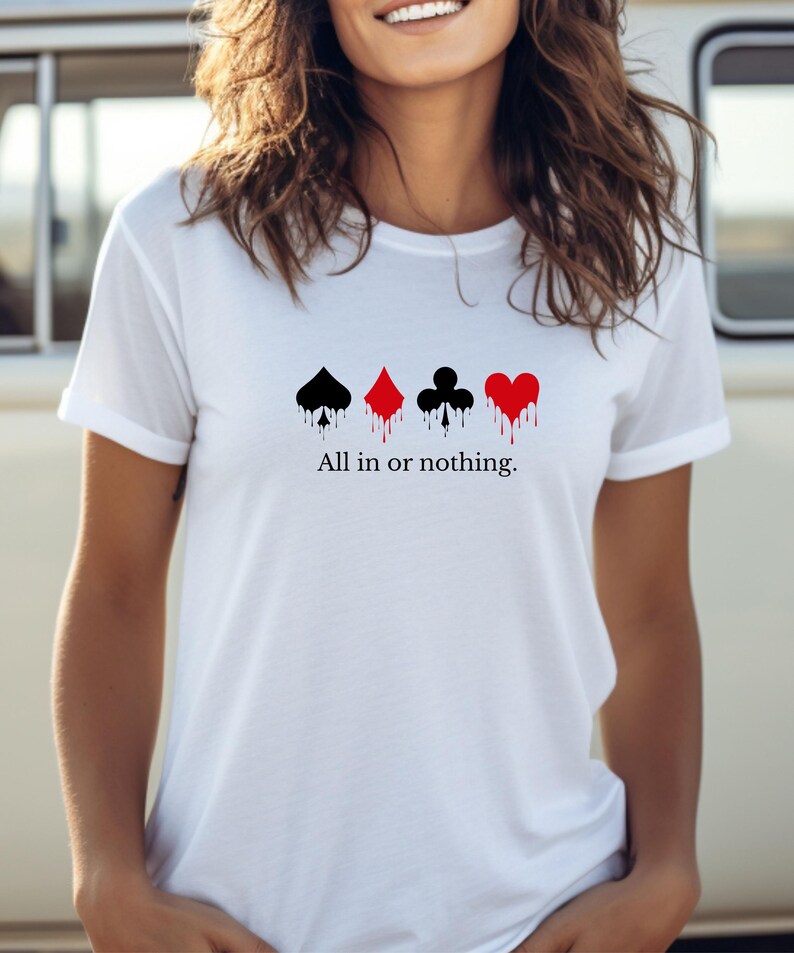 K&ouml;nnte beinhalten: Wei&szlig;es T-Shirt mit vier Spielkartenfarben: Pik, Karo, Kreuz und Herz, jeweils mit einem Tropfeffekt. Der Text "All in or nothing" ist darunter gedruckt.