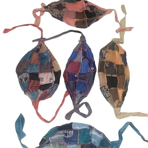 May include: Four face masks constructed from patchwork fabric squares in various colors including blue, brown, pink, and purple. Each mask features tie-straps on the sides and displays small white printed elephant motifs on some of the individual fabric patches.