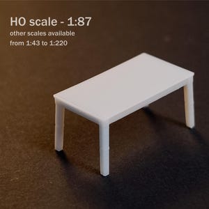 May include: A white miniature table in HO scale 1:87, with other scales available from 1:43 to 1:220. The rectangular table features a smooth flat top surface supported by four straight legs, presented as a small-scale model for hobbyists.