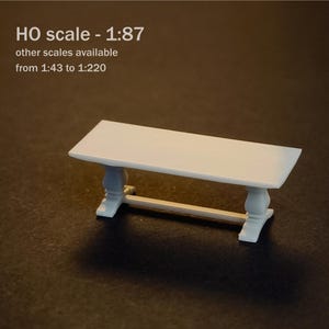 May include: A white miniature table with a rectangular top and two pedestal legs connected by a horizontal support bar. The text M HO scale - 1:87 other scales available from 1:43 to 1:220 is printed in the upper left corner of the image.