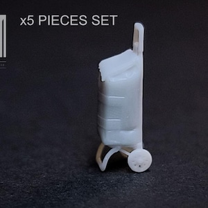 May include: A white miniature shopping trolley with a handle, a rectangular body, and two small wheels. The text "x5 PIECES SET" is above the trolley. The logo "M" is in the upper left corner.