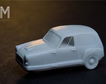 May include: A light gray model of a vintage delivery van. The miniature vehicle has a rounded body, a single front wheel, and a small windshield. The model is set against a dark background, with the logo "M" visible in the upper left corner.