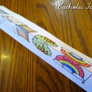 May include: A folded paper craft with illustrations of the books of Genesis and Exodus. The paper is white with colorful illustrations. The text "Genesis" and "Exodus" are visible.