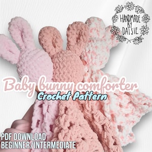 May include: A selection of handmade crochet baby bunny comforters in pink and white hues. The comforters feature bunny ear details and are crafted from soft, textured yarn. The image includes text that reads "Baby bunny comforter Crochet Pattern".
