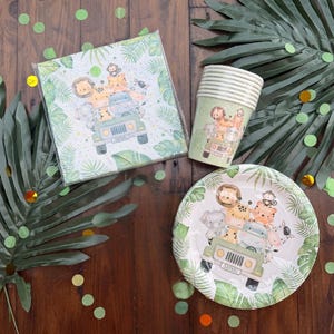Peut inclure: Ensemble de fournitures de fête sur le thème du safari, comprenant des serviettes, des gobelets en papier et une assiette. Les articles présentent des illustrations d'animaux de safari dans une jeep verte. Des feuilles de palmier vertes et des confettis sont éparpillés.