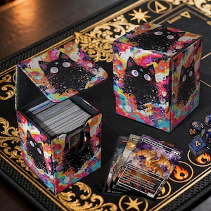 May include: Card storage box with a black cat design against a colorful, psychedelic background. The box is open, revealing a stack of cards. Dice and trading cards are also visible.