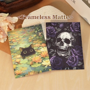 May include: Two rectangular prints with the text <Frameless Matte>. One print shows a black cat head emerging from a pond with orange and yellow water lilies. The other print features a human skull surrounded by dark purple roses and green leaves.
