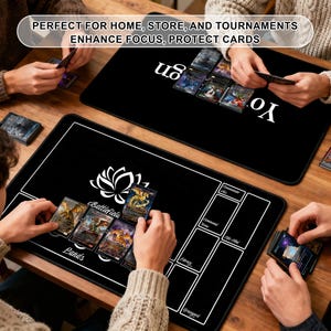 May include: Black rectangular gaming mats with white outlines and text. One mat features a lotus flower design and the word "Battlefield". The other mat has the word "us" in white. The mats are designed to enhance focus and protect cards.