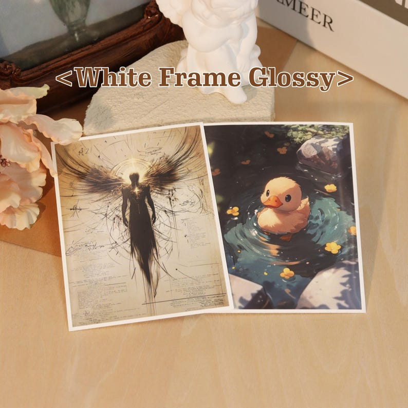 May include: Two rectangular glossy prints with white borders. The left print features a dark, winged silhouette against a beige background with technical lines. The right print shows a yellow duckling swimming in blue water with yellow flowers.