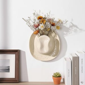 May include: A white ceramic mug with a black handle and the text "But First, Coffee" in a bold, black font. The mug is set against a blurred background, suggesting a cosy setting.