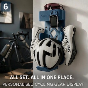 May include: A blue wall-mounted cycling gear organizer featuring a central slot for a digital bike computer, a top ledge for sunglasses, and side hooks holding a pair of white Specialized cycling shoes and a white and black bicycle helmet.