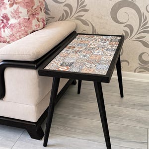 Mesa retangular de azulejo mexicano com acabamento em preto, tampo de mosaico cerâmico de 33 x 62 cm, mesa de apoio em madeira de pinho.