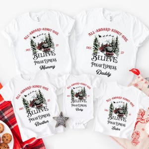 May include: A collection of five white shirts and one white baby bodysuit featuring a graphic of a red steam train in a snowy forest. The text reads ALL ABOARD ADMIT ONE, DEC 27, BELIEVE, POLAR EXPRESS, and individual labels for Mommy, Daddy, Brother, Sister, and Baby.