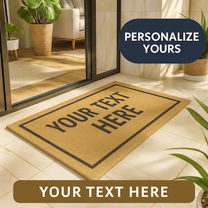 Può includere: Un zerbino rettangolare con la scritta "YOUR TEXT HERE" in nero, incorniciata da un bordo nero. Il tappeto è realizzato in un materiale color naturale ed è posto davanti a una porta a vetri. Le parole "PERSONALIZE YOURS" sono in un ovale blu scuro.