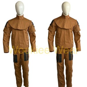 May include: Two brown costumes displayed on mannequins. Each costume includes a jacket with a high collar and shoulder accents, and matching pants with black accents. The costumes are made of a solid brown material.