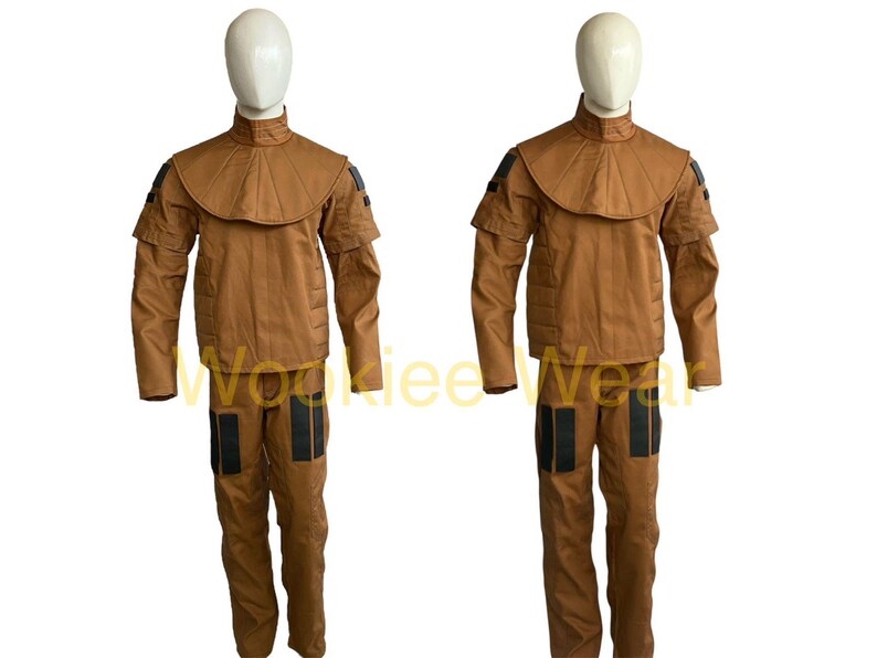May include: Two brown costumes displayed on mannequins. Each costume includes a jacket with a high collar and shoulder accents, and matching pants with black accents. The costumes are made of a solid brown material.