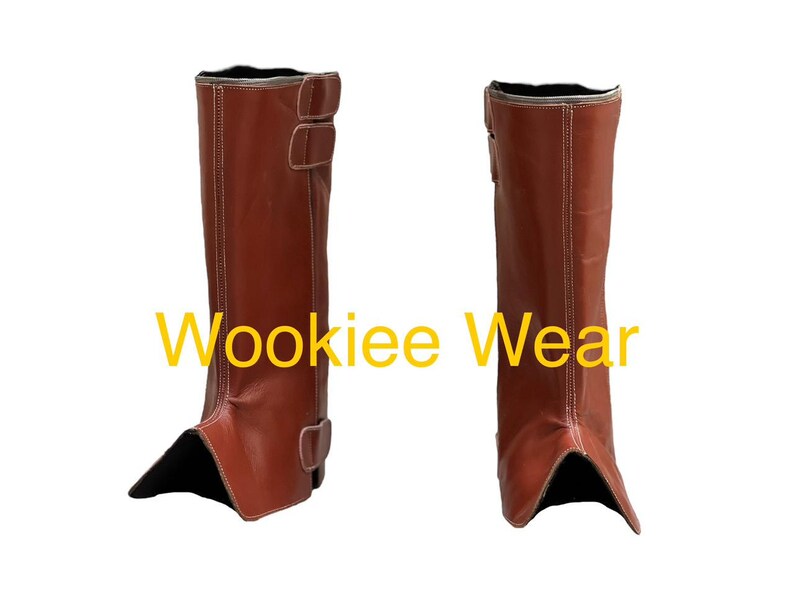 May include: A pair of brown leather boots with a knee-high design. The boots have two buckles on the side and white stitching. The text "Wookiee Wear" is displayed in yellow across the image.