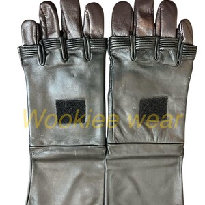 Pu&ograve; includere: Un paio di guanti in pelle nera con punte delle dita marroni. I guanti hanno un polsino lungo e un piccolo quadrato di velcro sul dorso di ogni mano. I guanti sono progettati per la protezione e probabilmente vengono utilizzati per il lavoro o il cosplay.