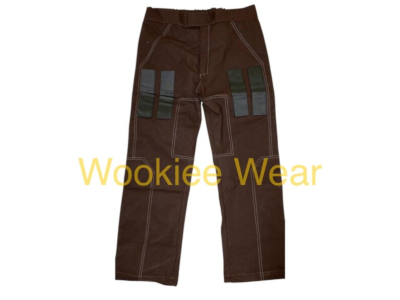 May include: Brown pants with white stitching and four rectangular patches on the front. The text "Wookiee Wear" is printed in yellow across the bottom of the image. These pants are likely part of a costume.