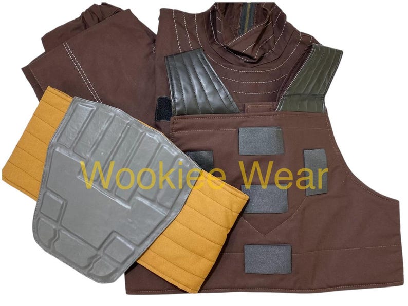 May include: A brown costume with a vest, shoulder pads, and a neck piece. The vest has black patches and the shoulder pads are gray and yellow. The neck piece has a brown and green design. The text "Wookiee Wear" is visible.