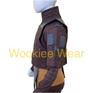May include: A brown costume jacket with a high collar and gray accents. The jacket has square patches on the sleeves and a tan midsection. The text "Wookiee Wear" is visible in yellow.