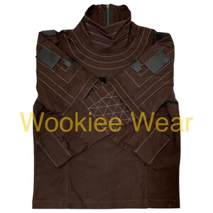 May include: Brown jacket with a high collar and a zipper. The jacket features white stitching details and patches on the shoulders and sleeves. The text "Wookiee Wear" is printed on the front.