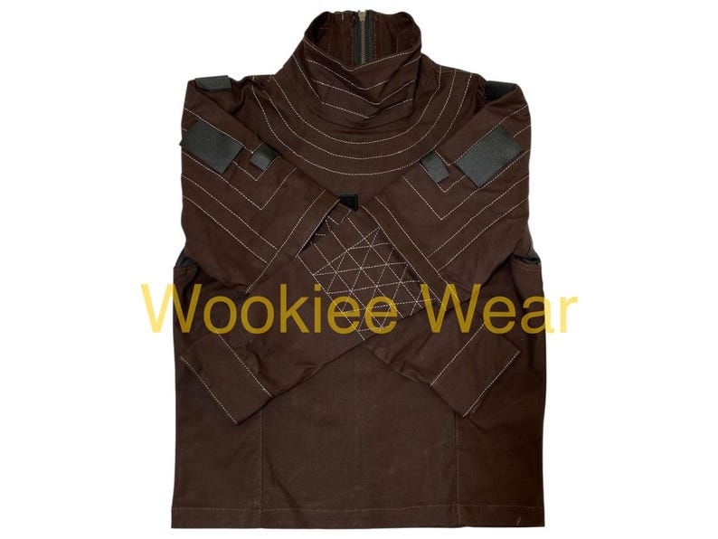 May include: Brown jacket with a high collar and a zipper. The jacket features white stitching details and patches on the shoulders and sleeves. The text "Wookiee Wear" is printed on the front.