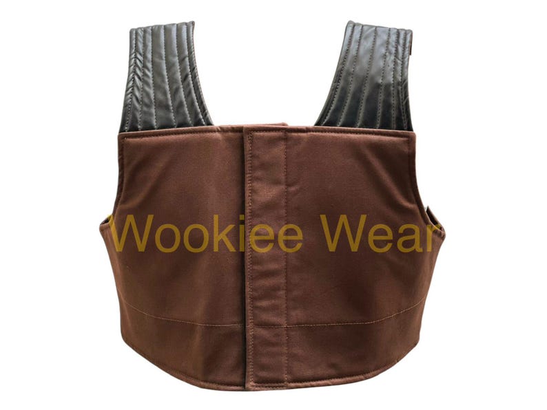 May include: Brown vest with black shoulder straps. The vest has a rectangular shape with a vertical seam down the front. The text "Wookiee Wear" is printed in gold on the front of the vest.