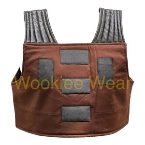 May include: Brown vest with black detailing and shoulder straps. The vest features four rectangular black patches on the front and the text "Wookiee Wear" in yellow.