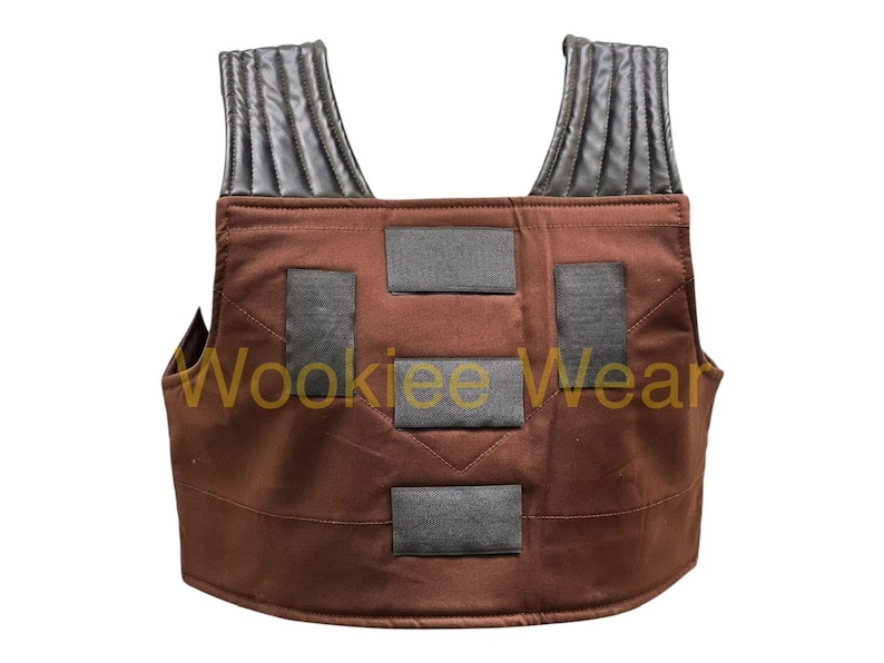 May include: Brown vest with black detailing and shoulder straps. The vest features four rectangular black patches on the front and the text "Wookiee Wear" in yellow.