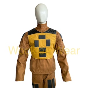 May include: A brown and yellow jumpsuit with black accents, displayed on a mannequin. The outfit features a yellow chest panel with a black cross design and black shoulder detailing. The sleeves and pants have black rectangular details.