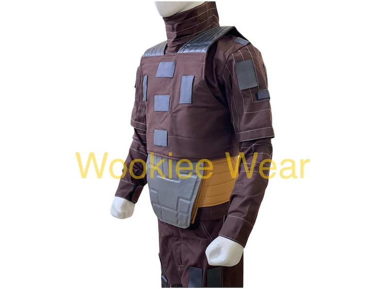 May include: Brown costume with gray accents, featuring a high collar and padded chest. The costume includes a belt and is designed with multiple square patches. The sleeves are long and the gloves are white.