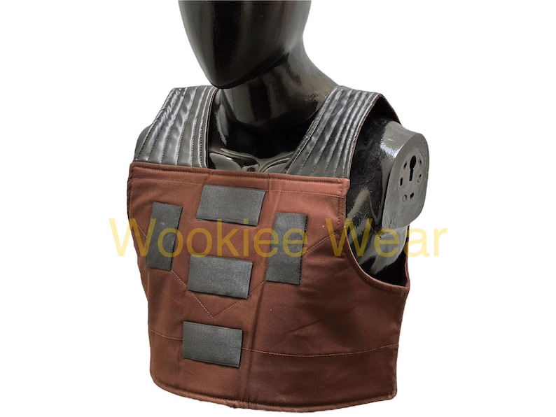 May include: A brown and black costume vest with rectangular black accents. The vest is displayed on a black mannequin. The text "Wookiee Wear" is visible in the image.
