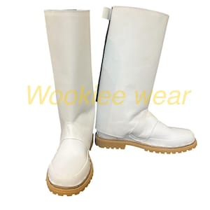 May include: A pair of white knee-high boots with a light brown sole. The boots have a smooth, clean design with a strap detail near the ankle. The text "Wookiee wear" is visible in the image.