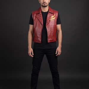 May include: A sleeveless dark red leather vest featuring a wide collar and a yellow flame-like graphic on the left chest. The vest is worn over a plain black short-sleeved t-shirt, paired with slim-fit black trousers and black sneakers with white soles.