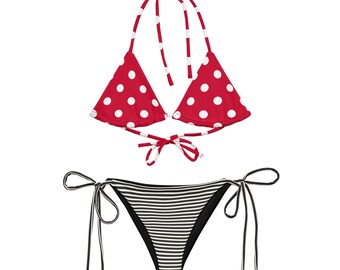 Puede incluir: Un conjunto de bikini de dos piezas que incluye un top triangular rojo con lunares blancos y tiras de sujeción a juego. La parte inferior es una braga de bikini con rayas horizontales negras y blancas y lazos laterales en las caderas.