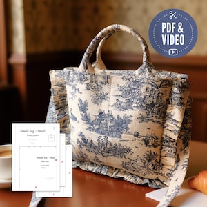 May include: A small tote bag with a blue and white toile pattern, featuring a ruffled edge and matching handles. The bag is displayed with sewing pattern instructions and a "PDF & VIDEO" icon.